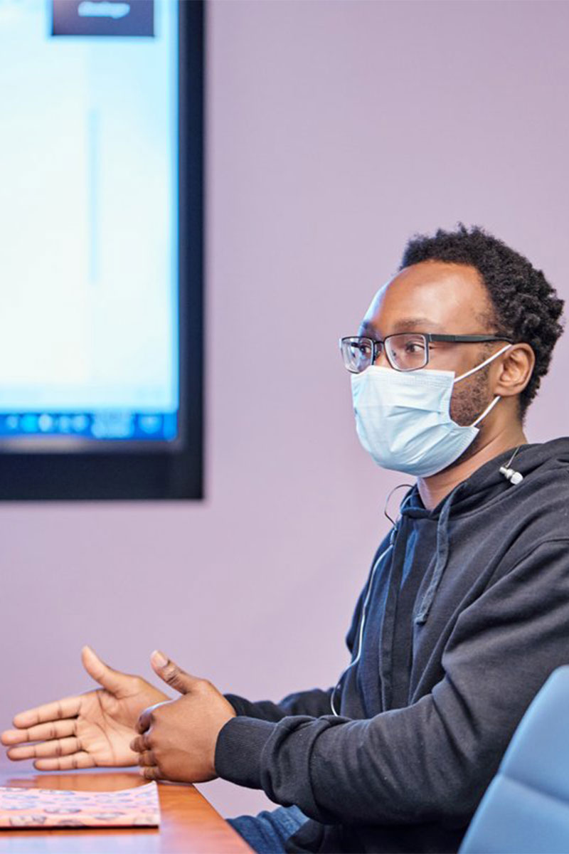 Candid of a masked Orna employee in a conference room